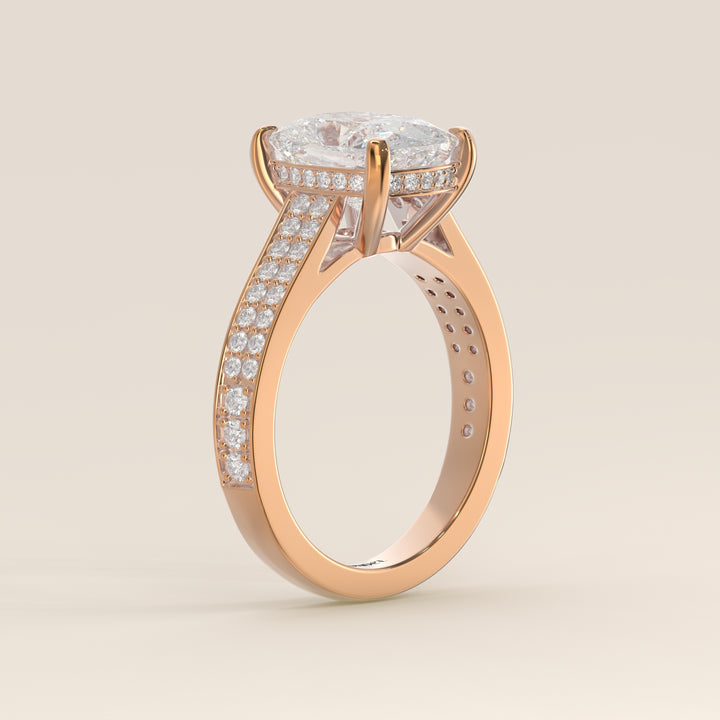 Bague de fiançailles en or rose, sertie d'un diamant de laboratoire taille coussin allongé, avec un large pavage, serti cathédrale et halo invisible.