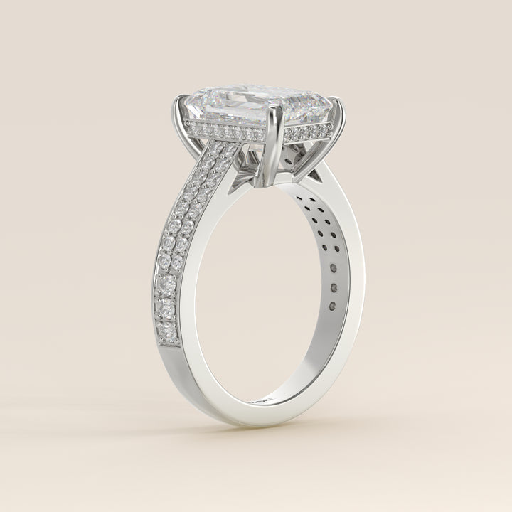Bague de fiançailles en or blanc, sertie d'un diamant émeraude de synthèse, serti d'un pavé large et d'un halo discret.