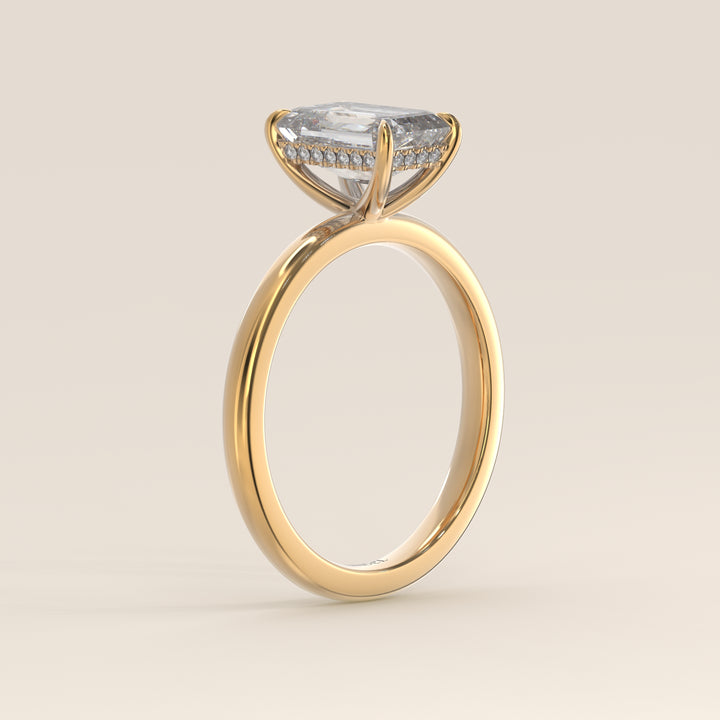 Bague de fiançailles en or jaune, sertie d'un diamant émeraude de synthèse avec halo discret.