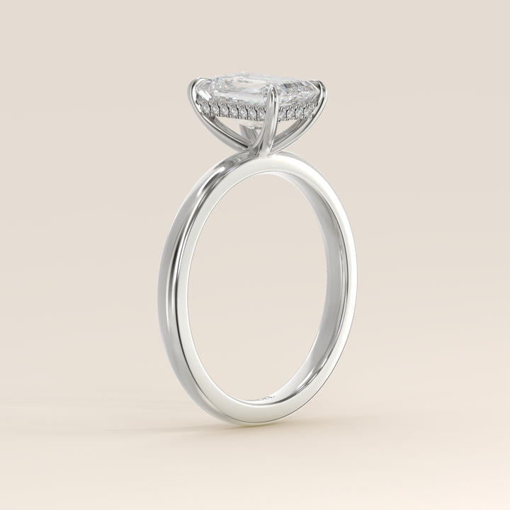 Bague de fiançailles en or blanc, sertie d'un diamant émeraude de laboratoire avec halo discret.