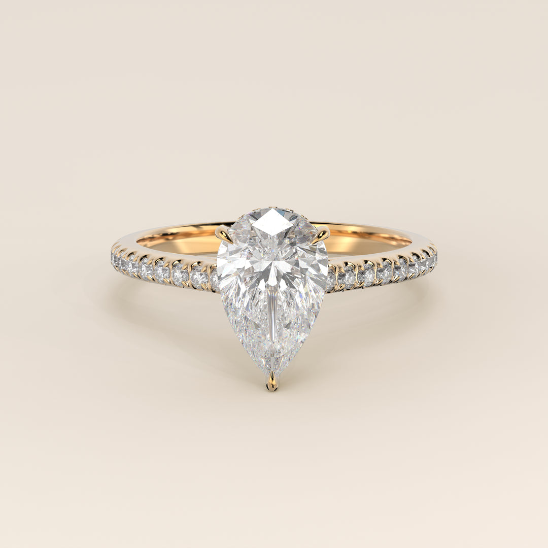 Bague de fiançailles en or jaune, sertie d'un diamant de laboratoire taille poire, avec pavage et halo discret sur l'anneau pavé.
