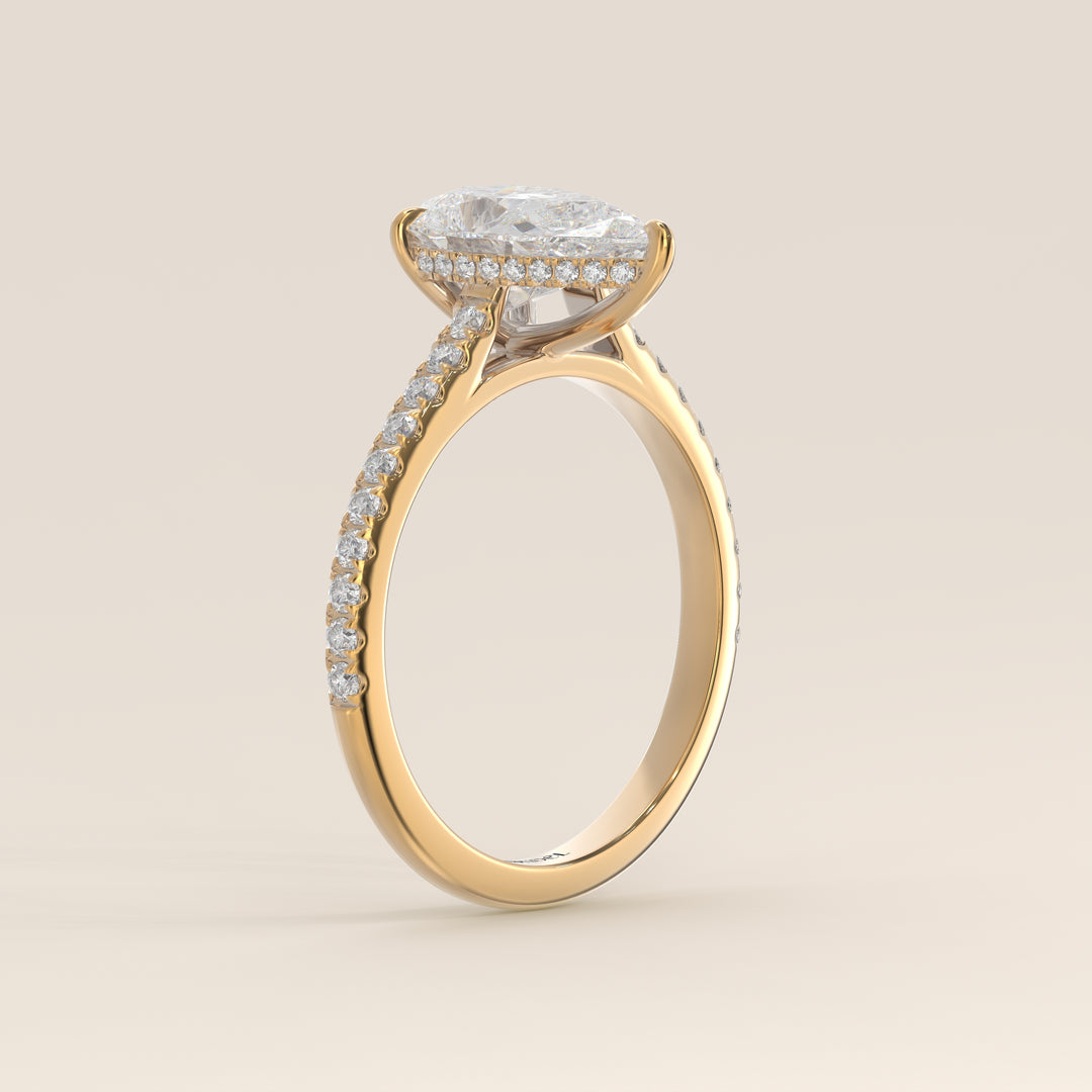 Bague de fiançailles en or jaune, sertie d'un diamant de laboratoire taille poire, avec pavage et halo discret sur l'anneau pavé.