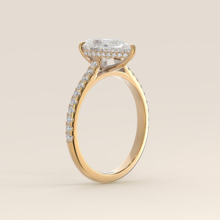Bague de fiançailles en or jaune, sertie d'un diamant de laboratoire taille poire, avec pavage et halo discret sur l'anneau pavé.