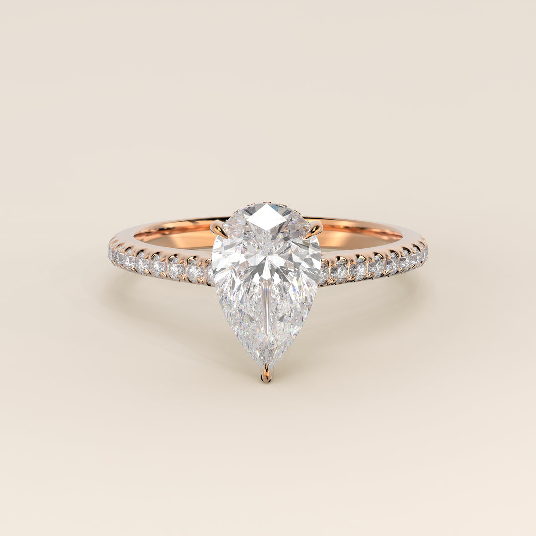 Bague de fiançailles en or rose, sertie d'un diamant de laboratoire taille poire, avec pavage et halo discret sur l'anneau pavé.