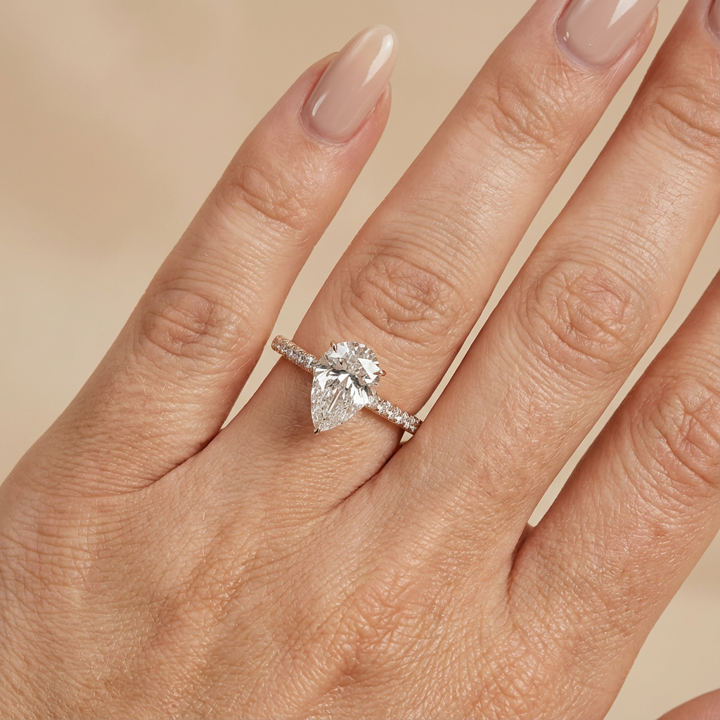 Bague de fiançailles en or rose, sertie d'un diamant de laboratoire taille poire, avec pavage et halo discret sur l'anneau pavé.