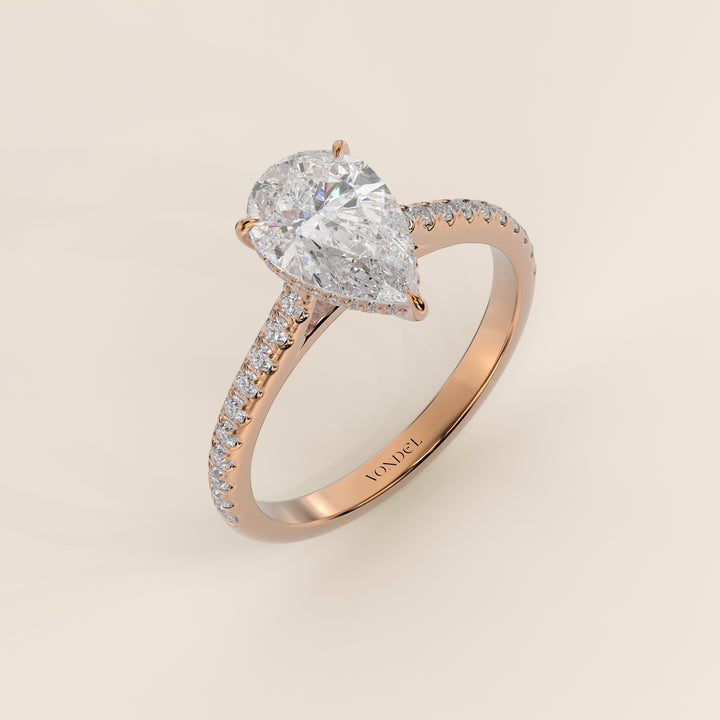Bague de fiançailles en or rose, sertie d'un diamant de laboratoire taille poire, avec pavage et halo discret sur l'anneau pavé.