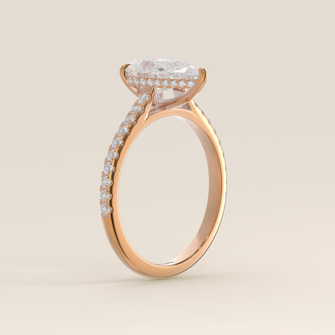 Bague de fiançailles en or rose, sertie d'un diamant de laboratoire taille poire, avec pavage et halo discret sur l'anneau pavé.