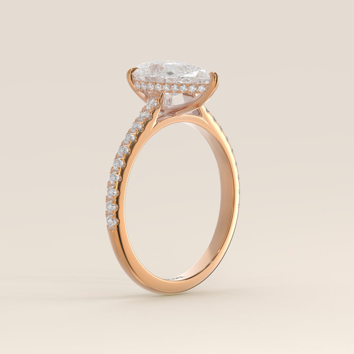 Bague de fiançailles en or rose, sertie d'un diamant de laboratoire taille poire, avec pavage et halo discret sur l'anneau pavé.