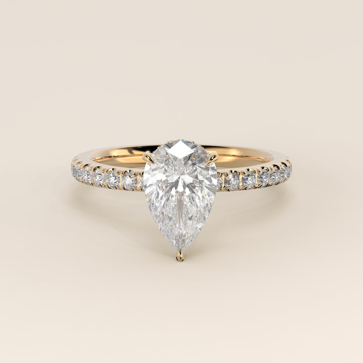 Bague de fiançailles en or jaune, sertie d'un diamant poire de laboratoire avec halo discret et pavage sur l'anneau.