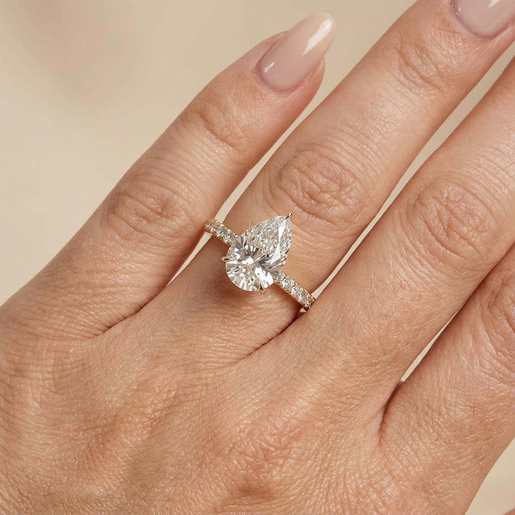 Bague de fiançailles en or jaune, sertie d'un diamant poire de laboratoire avec halo discret et pavage sur l'anneau.
