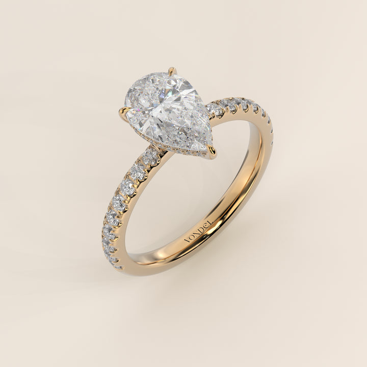 Bague de fiançailles en or jaune, sertie d'un diamant poire de laboratoire avec halo discret et pavage sur l'anneau.