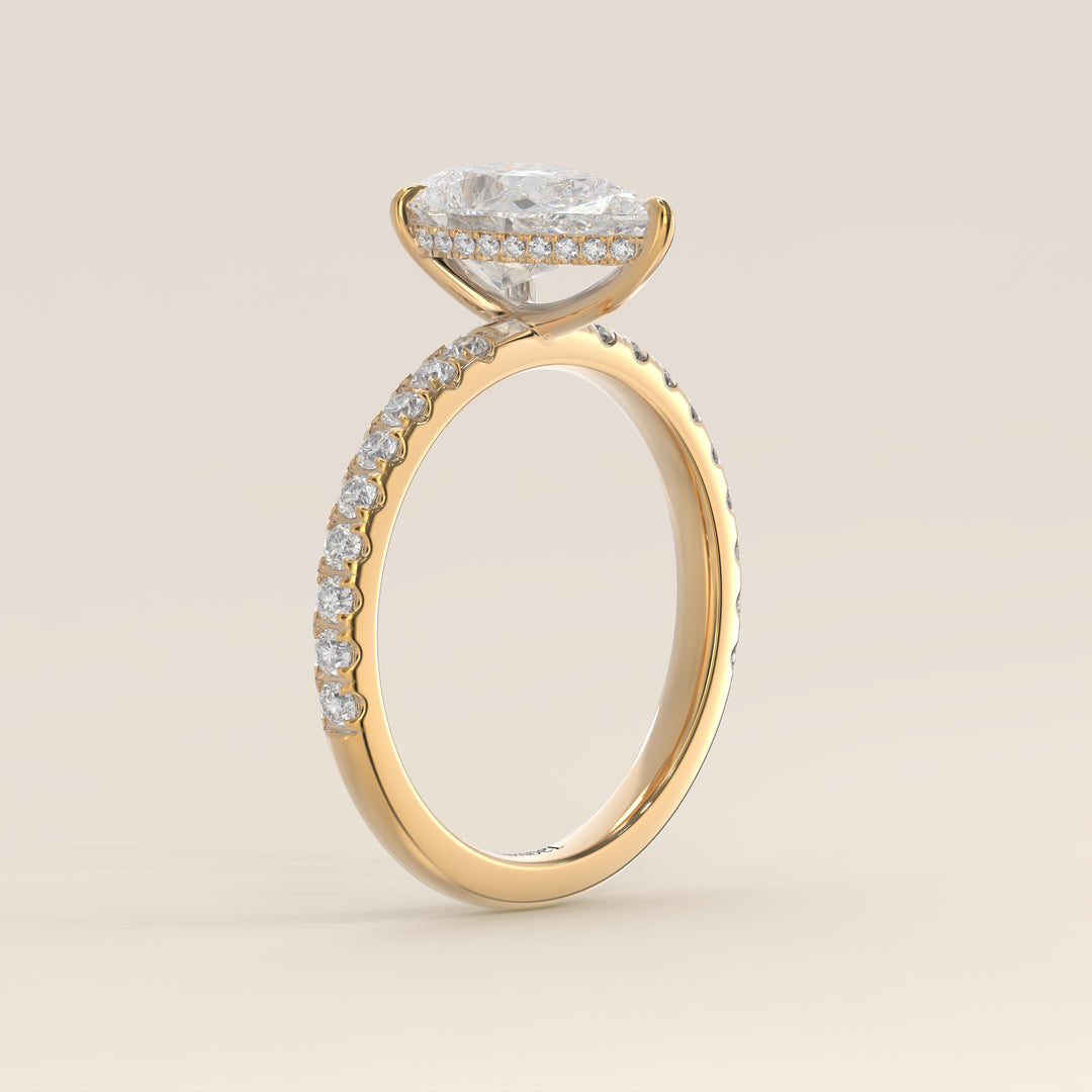 Bague de fiançailles en or jaune, sertie d'un diamant poire de laboratoire avec halo discret et pavage sur l'anneau.