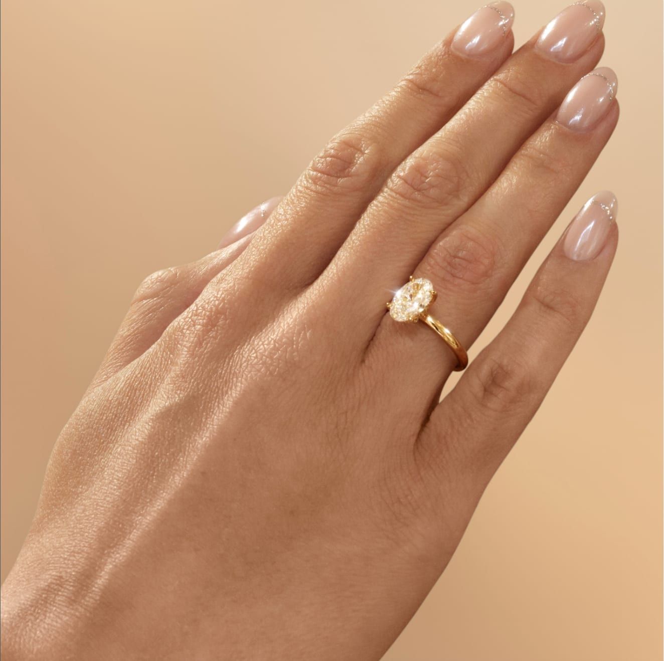 Ovale solitaire verlovingsring in geelgoud, aan de hand